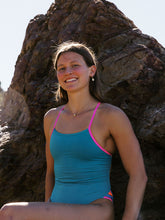 Athlete Kate wears the fixed back Zambia one piece in the colour Atlantic, the suit has contrasting pink sorbet straps and mid coverage.