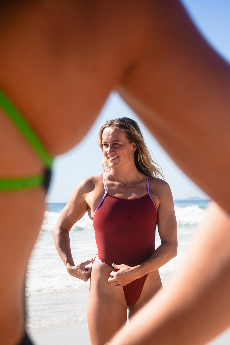 Framed by the arm of fellow athlete, surf life saving athlete Liv Corrin steals the spotlight in the JAYD Swimwear Zambia one piece, with bold contrasting cinnamon and lilac haze pops of colour.