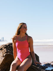 Athlete Molly wearing the Lennox one piece designed by JAYD Swimwear in the colour Pink Sorbet. this fixed back one piece is perfect for catching waves at the beach.