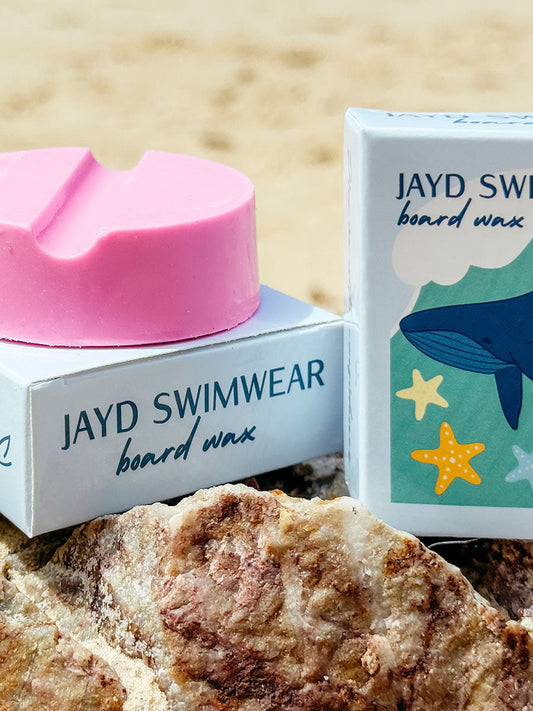 Pink surf wax with close up of JAYD Swimwear packaging. 